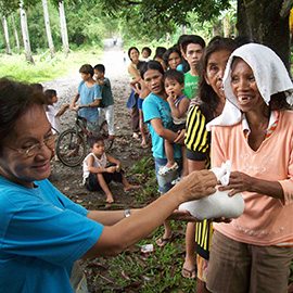 Eine freiwillige Helferin für Mary’s Meals gibt in den Philippinen Hilfspakete aus